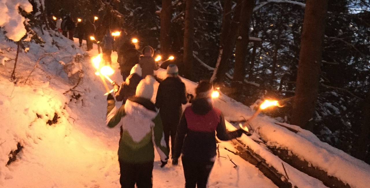 Gruppe mit Fackeln durch den Schnee laufend