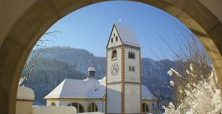 Blick auf den verschneiten Kirchturm der Kirche St. Mang in Füssen