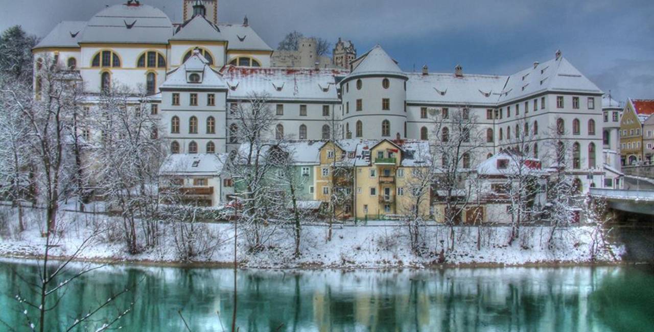 Blick über den Lech auf das verschneite Kloster St. Mang in Füssen