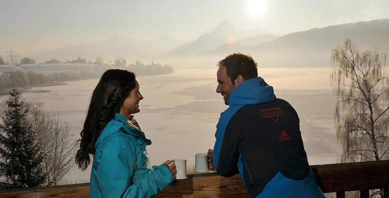 Genießen Sie die romantische abendstimmung in Füssen bei einem warem Getränk und genießen Sie den Blick auf die vereiste Seeenlandschaft.